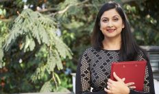 Successful smiling Indian businesswoman with bright red leather folder standing outdoors